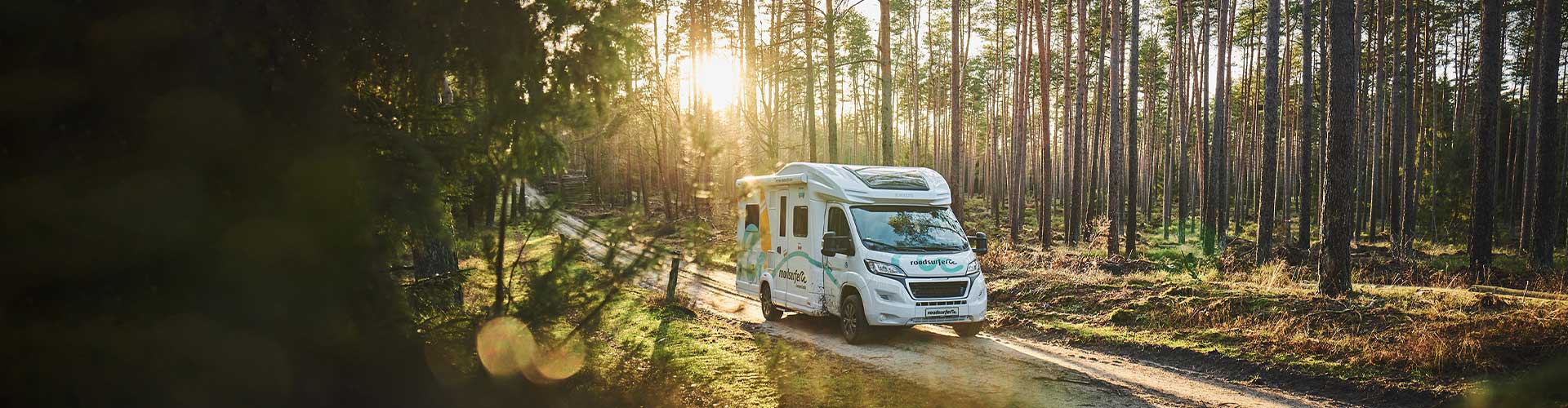 roadsurfer RV in a sunny forest