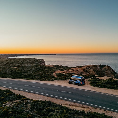 roadsurfer RV parked near the coastline at sunset
