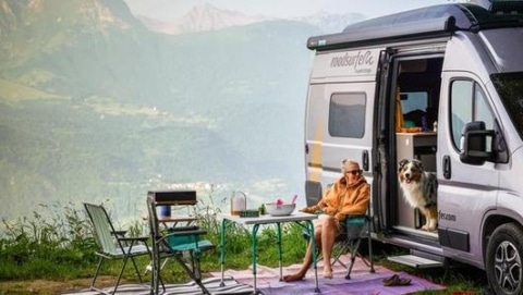 RV campaign showing a camper van set up at a mountain camping spot with outdoor seating and scenic views