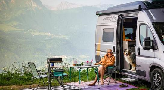 RV campaign showing a camper van set up at a mountain camping spot with outdoor seating and scenic views