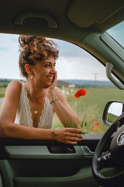 Woman leaning at an RV window holding a flower for an RV classes guide