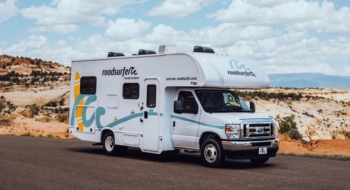 A roadsurfer RV on a quiet desert highway, showing the kind of rental you’d want good RV insurance for on a road trip