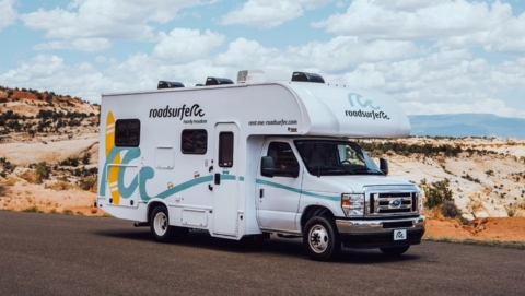 A roadsurfer RV on a quiet desert highway, showing the kind of rental you’d want good RV insurance for on a road trip