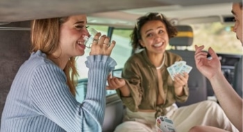 Three people sitting inside an RV playing cards together during a relaxed travel moment