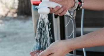 Person testing water flow from an RV's outdoor shower hose held over their hand