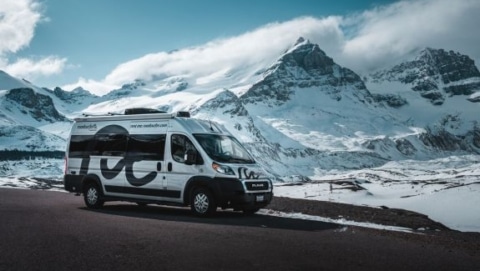 RV parked beside a snowy mountain road in winter