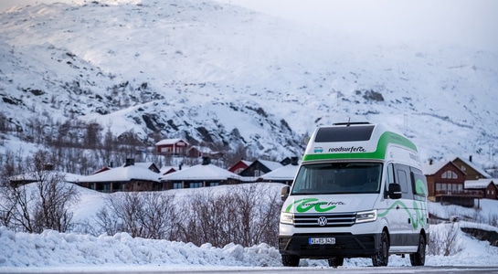 Big green and white RV driving through a snowy road in Sweden