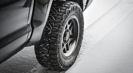 Winter tire on a vehicle driving over a snowy road