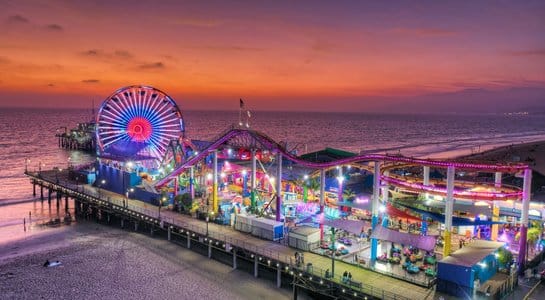 Santa Monica Pier illuminated at night with Ferris wheel and ocean, a vibrant stop on a California RV road trip