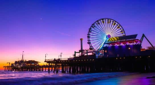 Colorful sunset over Santa Monica Pier with Ferris wheel lights reflecting on the ocean