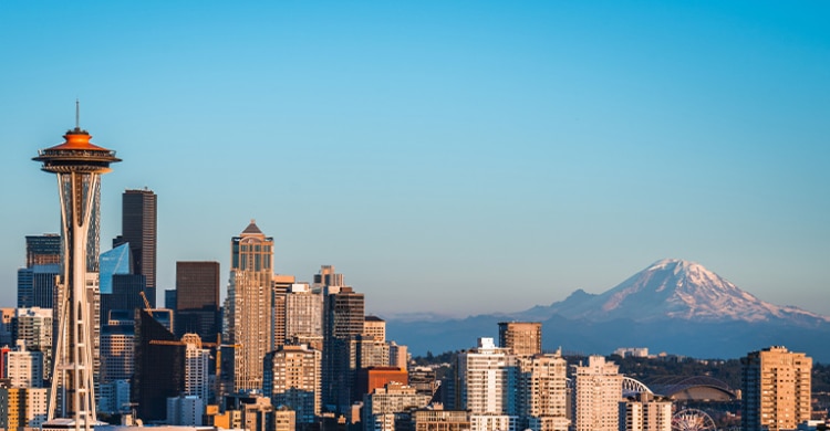 Seattle skyline on a sunny day with space needle in the front and Mount Rainier in the back.