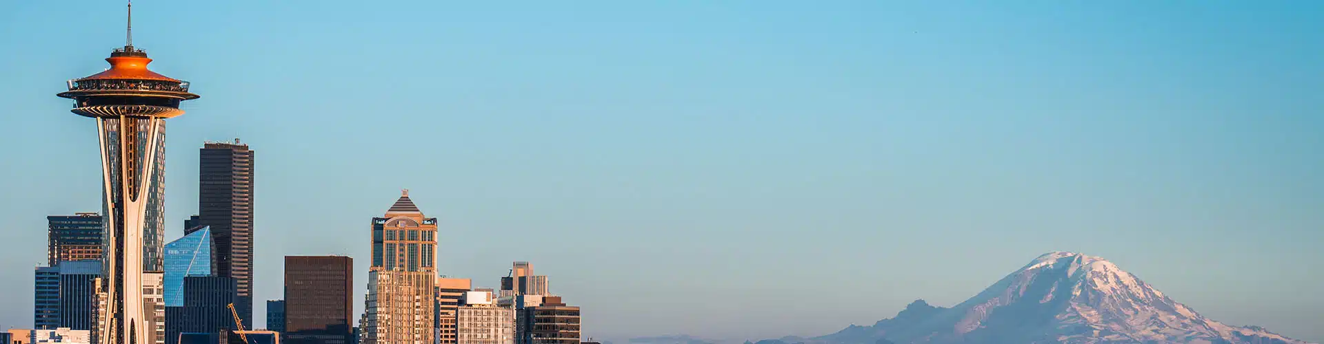 Seattle skyline on a sunny day with space needle in the front and Mount Rainier in the back.