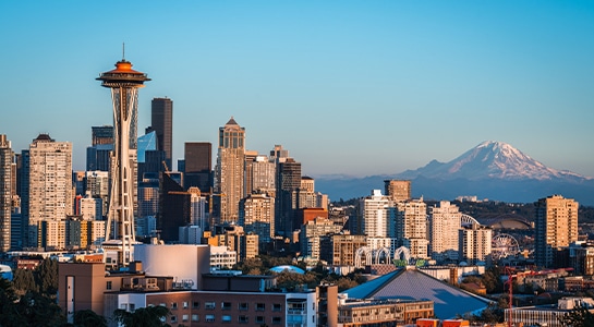 Seattle skyline on a sunny day with space needle in the front and Mount Rainier in the back.