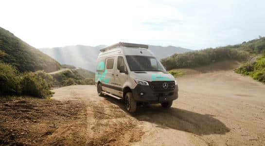 A small RV rental driving along a dirt road in a remote outdoor setting, perfect for off-grid exploration.