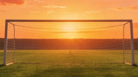 Field goal in soccer stadium captured during sunset.