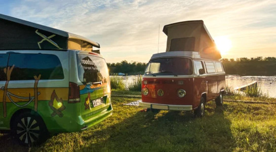 two colorful vans at a lake on a roadsurfer spot
