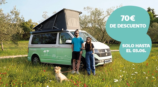 Couple with a dog in front of a camper van in the nature during spring