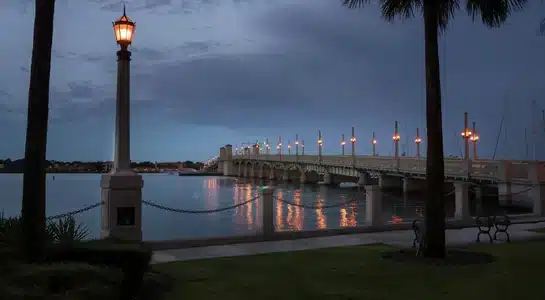 The Bridge of Lions lit by lamps at dusk reflecting on the Matanzas River in St. Augustine, Florida.