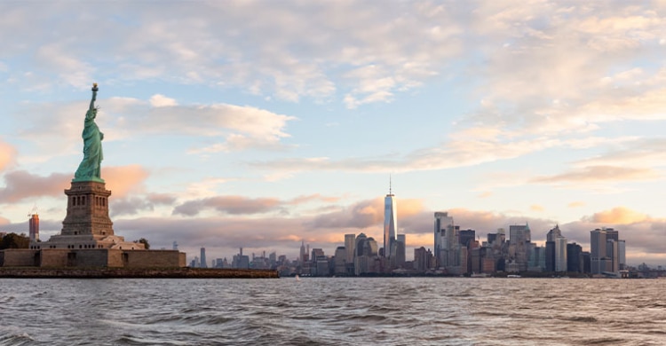 Statue of Liberty in New York seen from the water with the skyline of New York City in the background.
