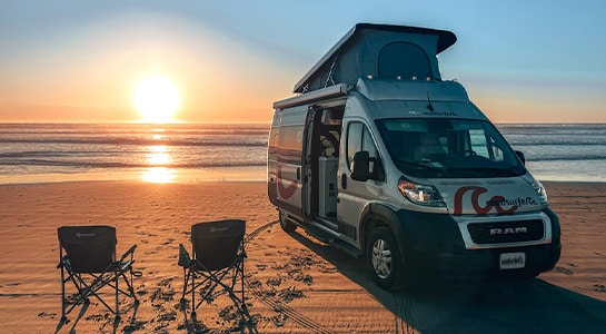 Sunset at the beach with a motorhome and two camping chairs in the usa