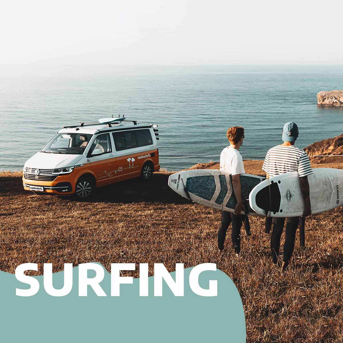Surfing: Campervan am Meer mit zwei Personen mit Surfbrett im Vordergrund
