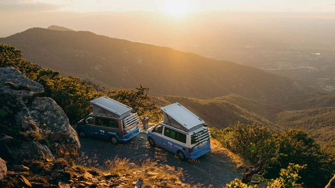 two campervans st sunset standing on a hill with scenic view over hills