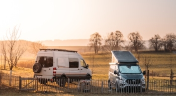 Two campervans on a lawn in winter at sunrise