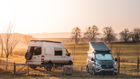 Two campervans on a lawn in winter at sunrise