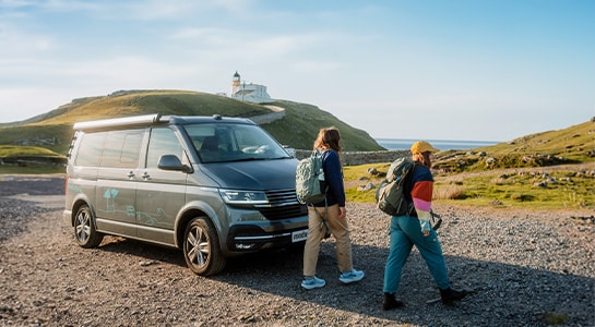 Two people walking away from a parked campervan.