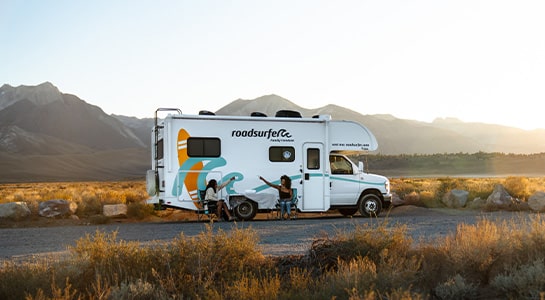 Two Women Cheersing In Front Of An Rv At Sunset