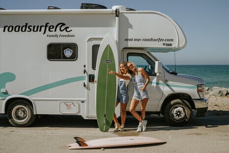 Two women stand with surboards