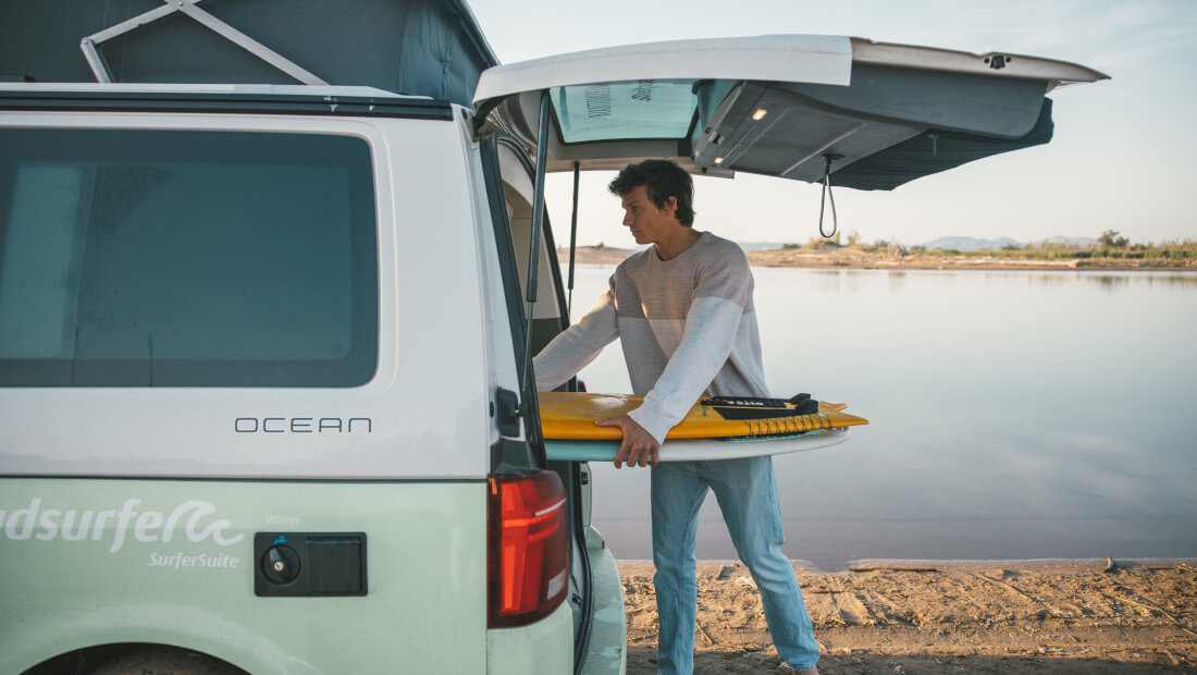 man getting surfboards out of the trunk of a van