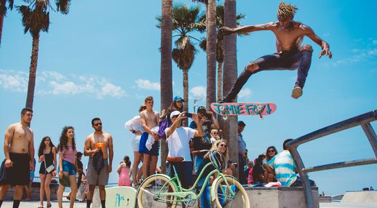 Skateboarder performing a trick at Venice Beach skate park with crowd watching