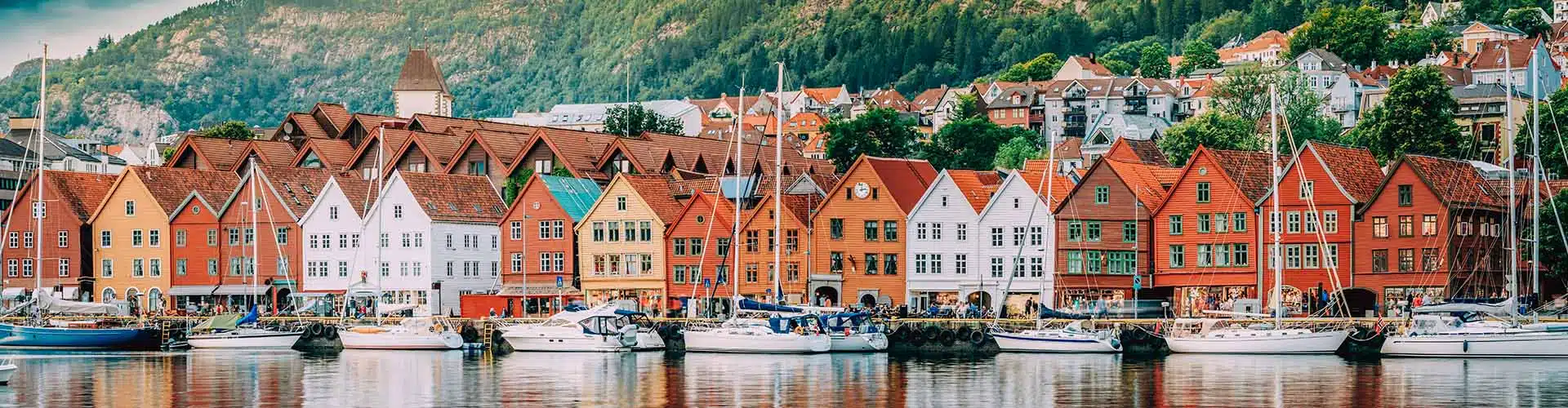Historical houses with sailing boats in front in a harbour in Bryggen in Bergen in Norway