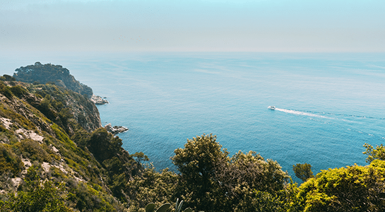 Bird view over the sea showing a tiny boat going by