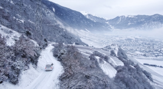 VW Campervan driving in the mountains covered in snow