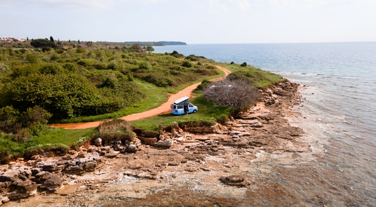 A blue VW camper standing next to the coast in Catalonia, Spain