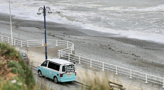 A turquoise VW campervan parked by the beach in Wales