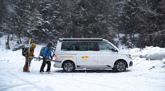 Two people set off for ski tour from a VW campervan