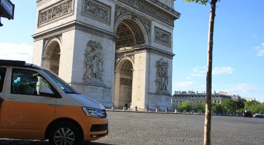 Yellow VW California camper standing in front of the arc de triomphe in Paris