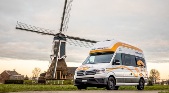 white campervan in front of a windmill