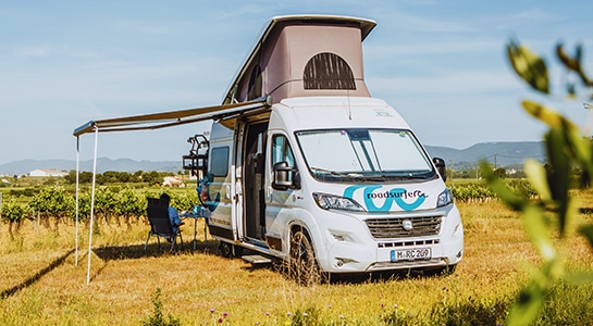 white motorhome with pop up roof parked in a vineyard