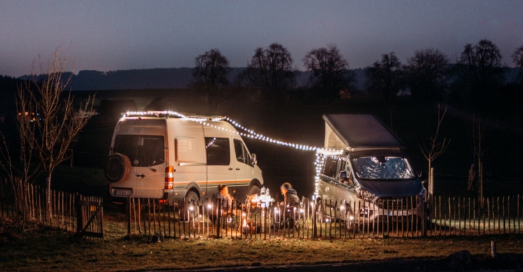 two campervans at night in winter, fairylights
