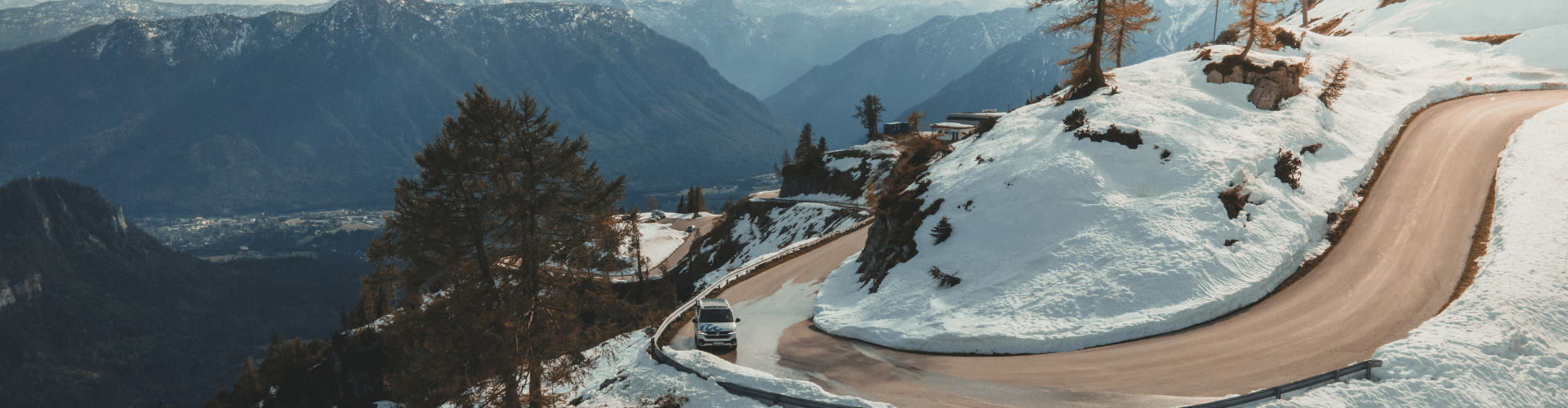 camper van driving on a snowy mountain road during winterizing an RV trip