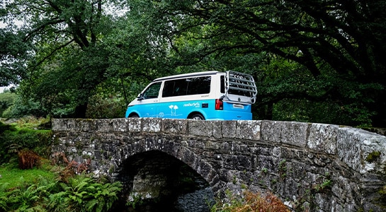 Campervan driving over a stone bridge
