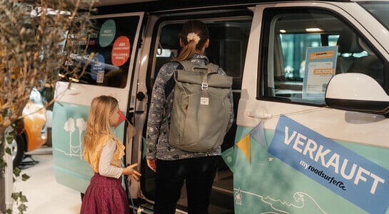 Woman and child looking into campervan at fair.