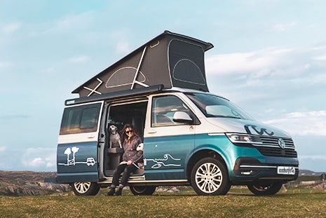 Woman and dog sat in open campervan