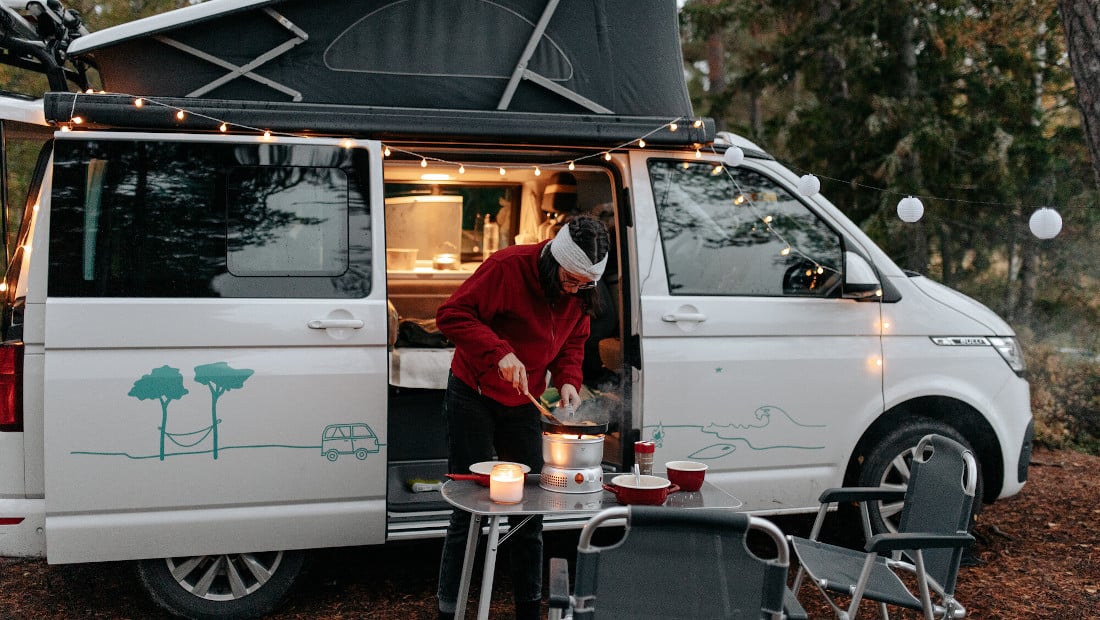 woman cooking in front of a camper van