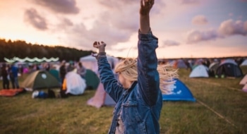 Woman dancing at festivals with tents set up all around her.