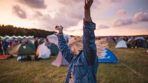Woman dancing at festivals with tents set up all around her.
